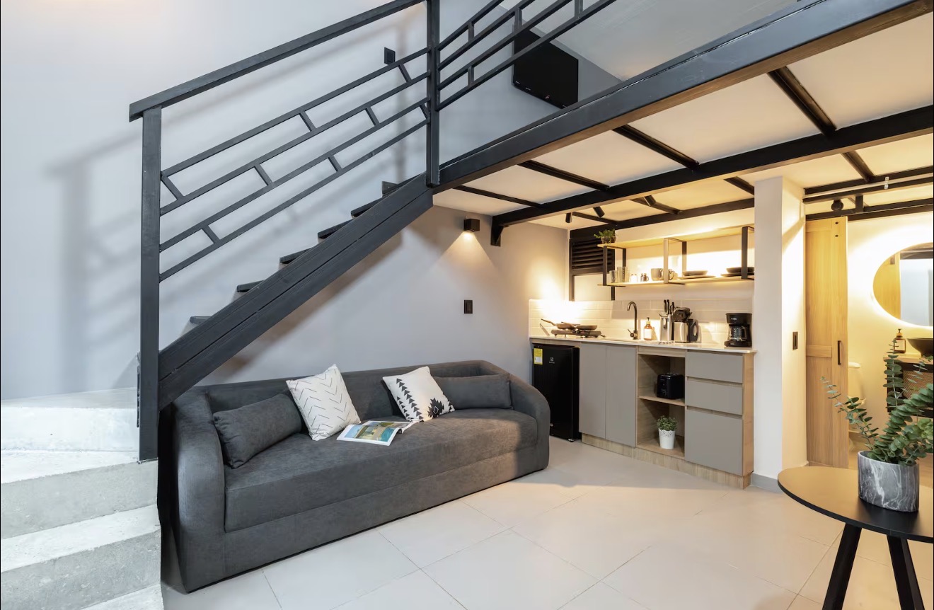 AL102 — living area with sofa, stairs to loft and kitchenette
